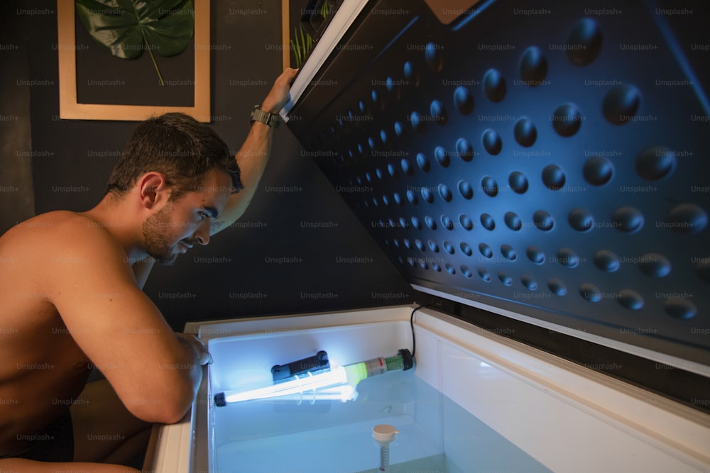 a shirtless man is looking into an open refrigerator