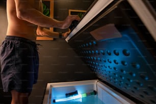 Un homme ouvre un réfrigérateur avec une lumière à l’intérieur