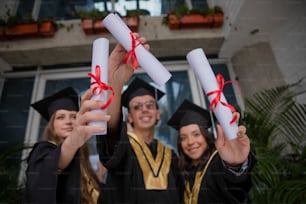 a group of people in graduation gowns holding up diplomas