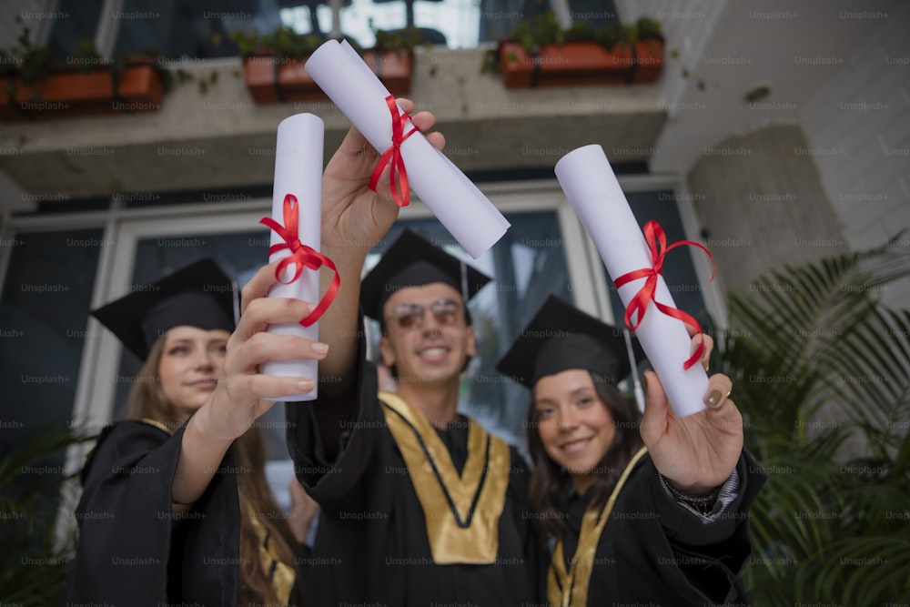 a group of people in graduation gowns holding up diplomas