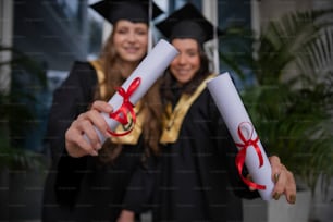 a couple of women in graduation gowns holding diplomas