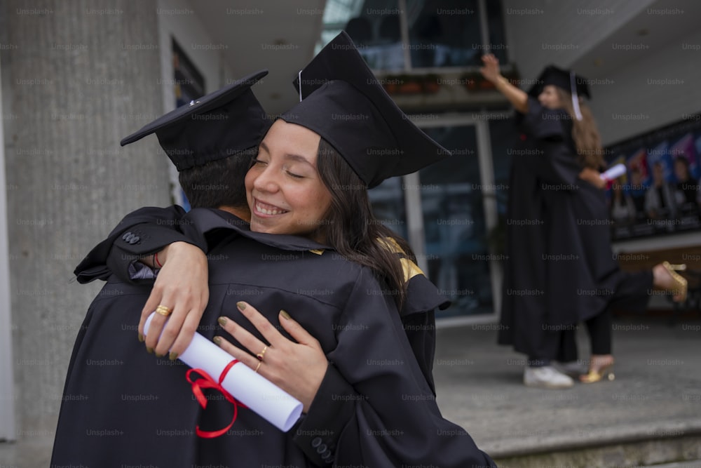 a woman in a graduation gown hugging another woman