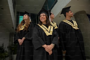 un gruppo di persone in piedi l'una accanto all'altra in abiti da laurea