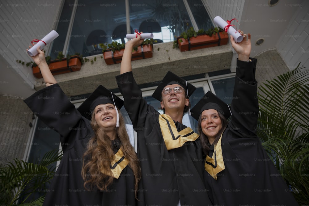 a group of people in graduation gowns holding up their hands