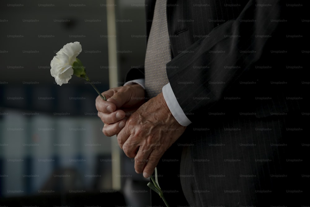 a man in a suit holding a white flower