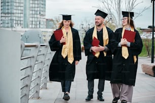 a group of three graduates walking across a bridge