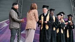 un gruppo di persone in abiti da laurea in piedi su un palco