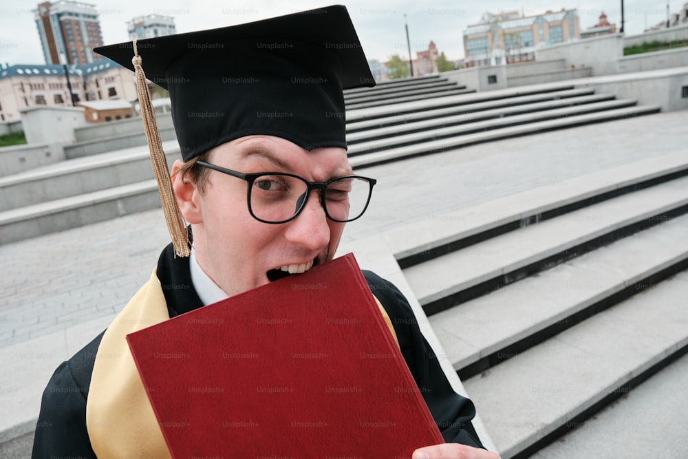 un uomo in un berretto e un abito da laurea che tiene in mano un libro