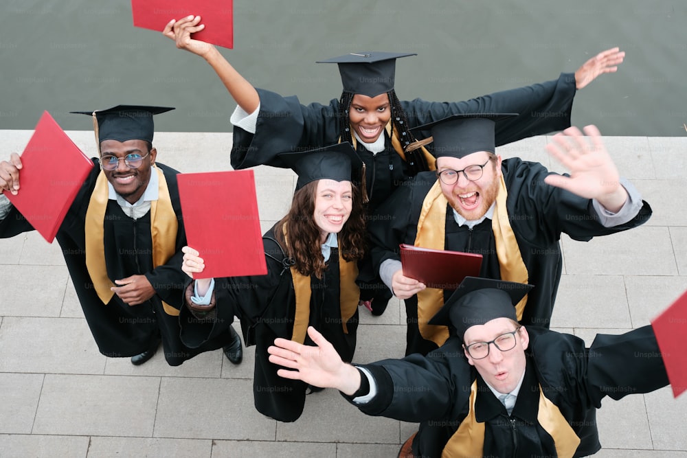 a group of people wearing graduation gowns and holding red folders