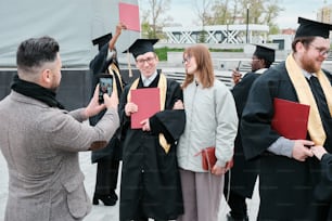 Un homme prend une photo d’un groupe de diplômés