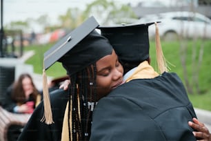 a woman in a graduation cap and gown hugging another woman