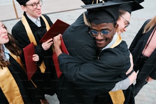 un uomo in un berretto e un abito che abbraccia una donna in un abito da laurea