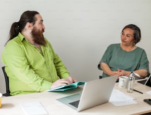 two people sitting at a table with a laptop