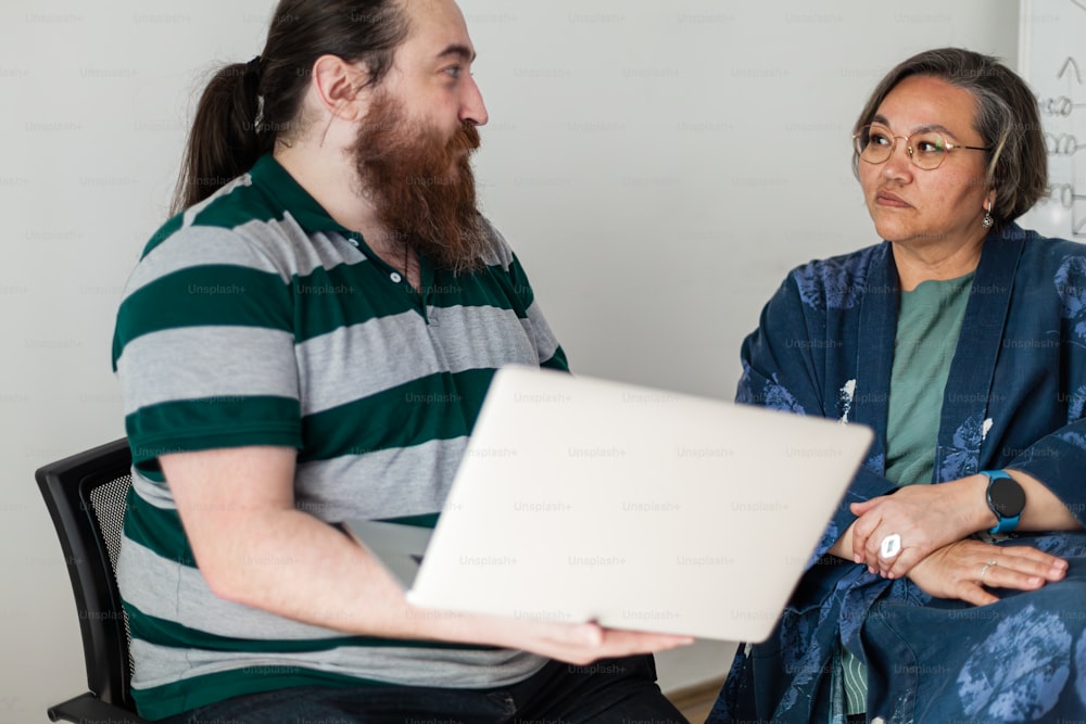 a man with a beard sitting next to a woman with a laptop
