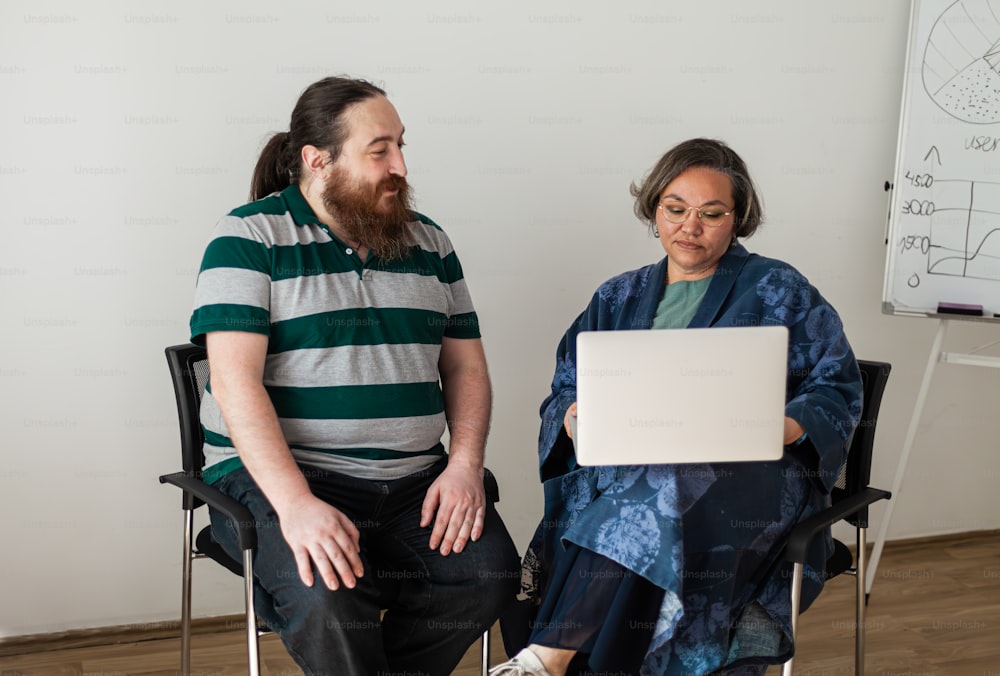 un homme avec une barbe assis à côté d’une femme avec un ordinateur portable