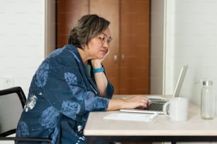 a woman sitting at a table using a laptop computer