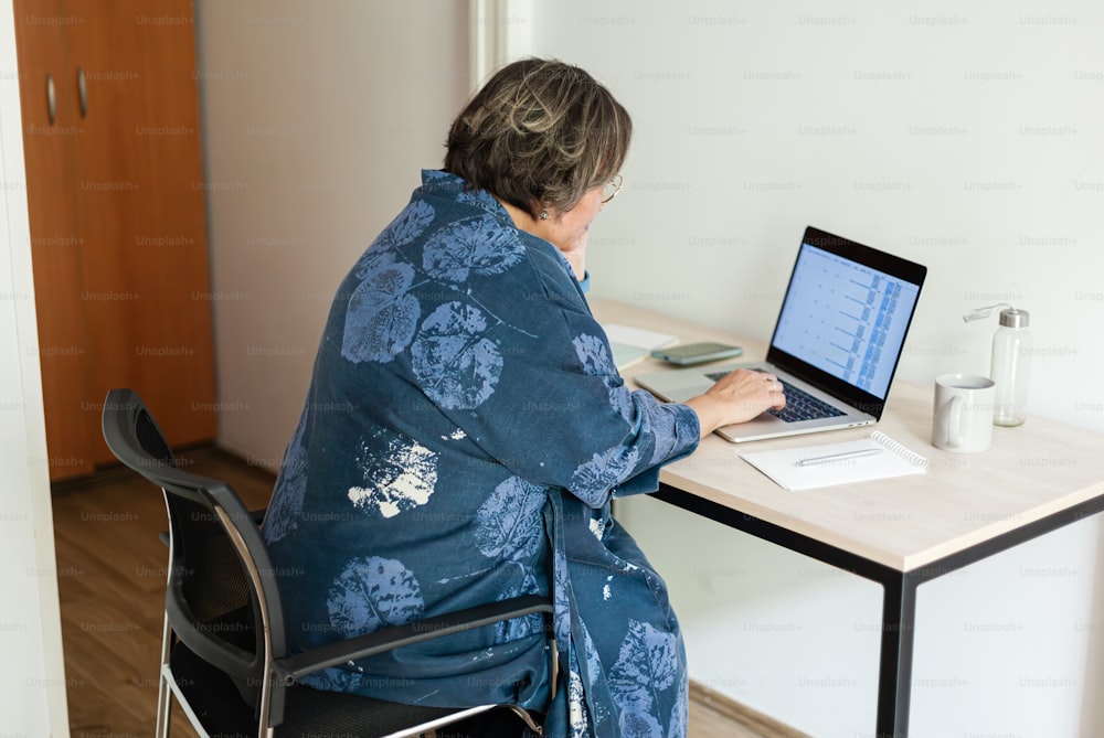 eine Frau, die an einem Schreibtisch sitzt und einen Laptop benutzt