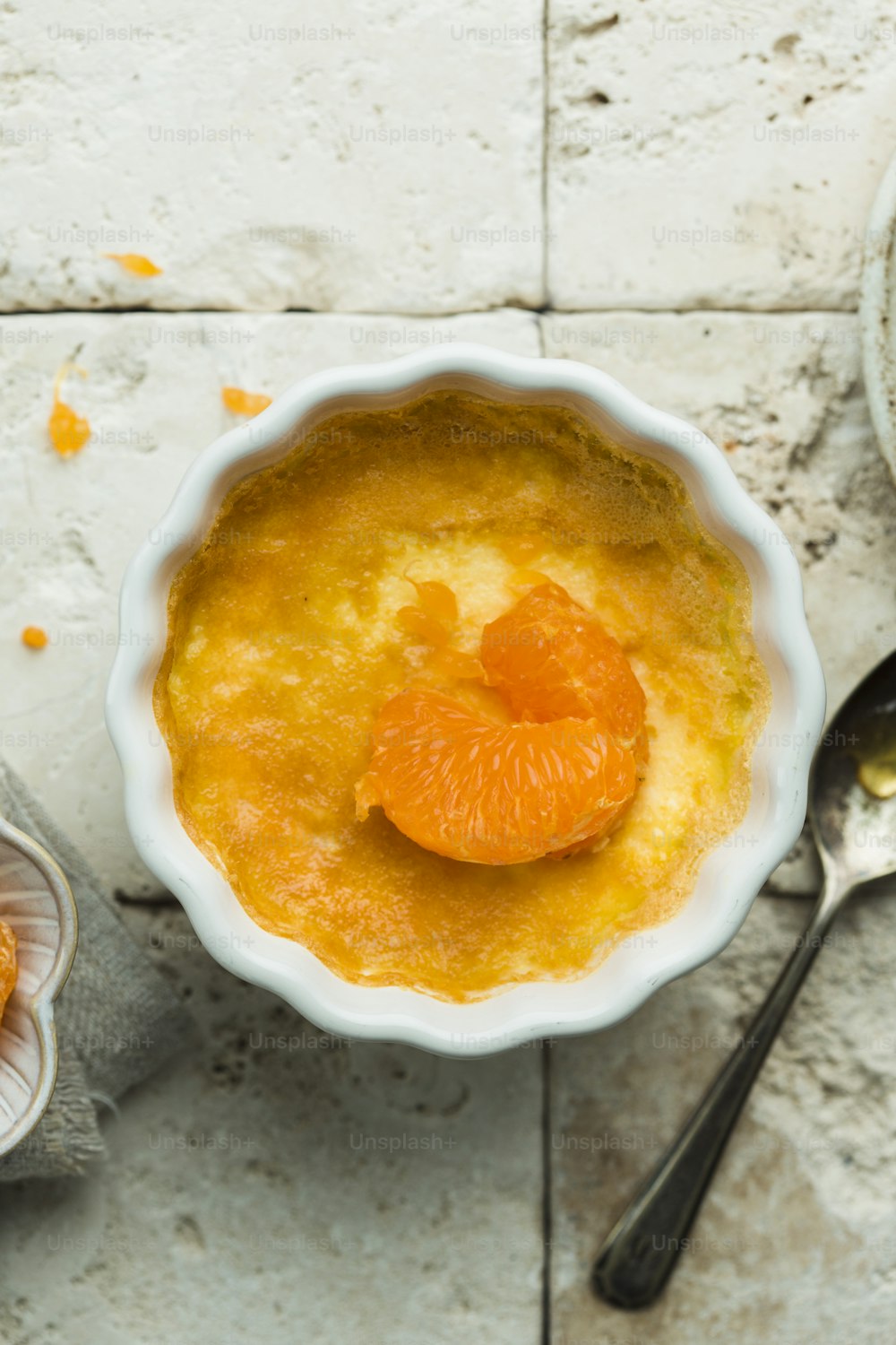 a bowl of orange custard with a spoon next to it