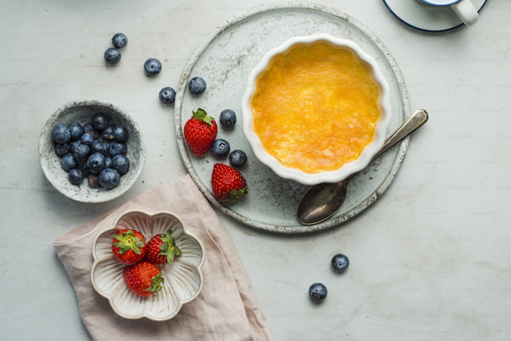 a bowl of orange custard next to a bowl of blueberries