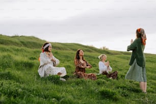 a group of women sitting on top of a lush green hillside