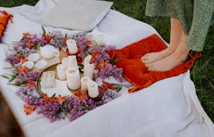 a person laying on a blanket with candles and flowers
