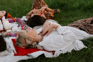 two women laying on a blanket in the grass