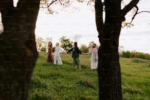 a group of people walking across a lush green field