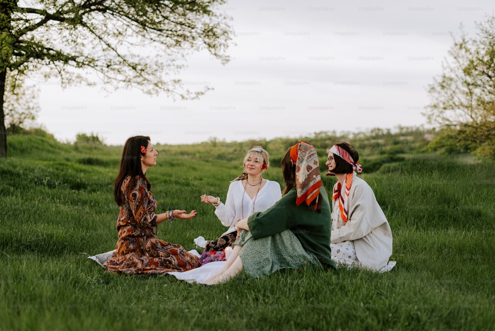 a group of women sitting on top of a lush green field