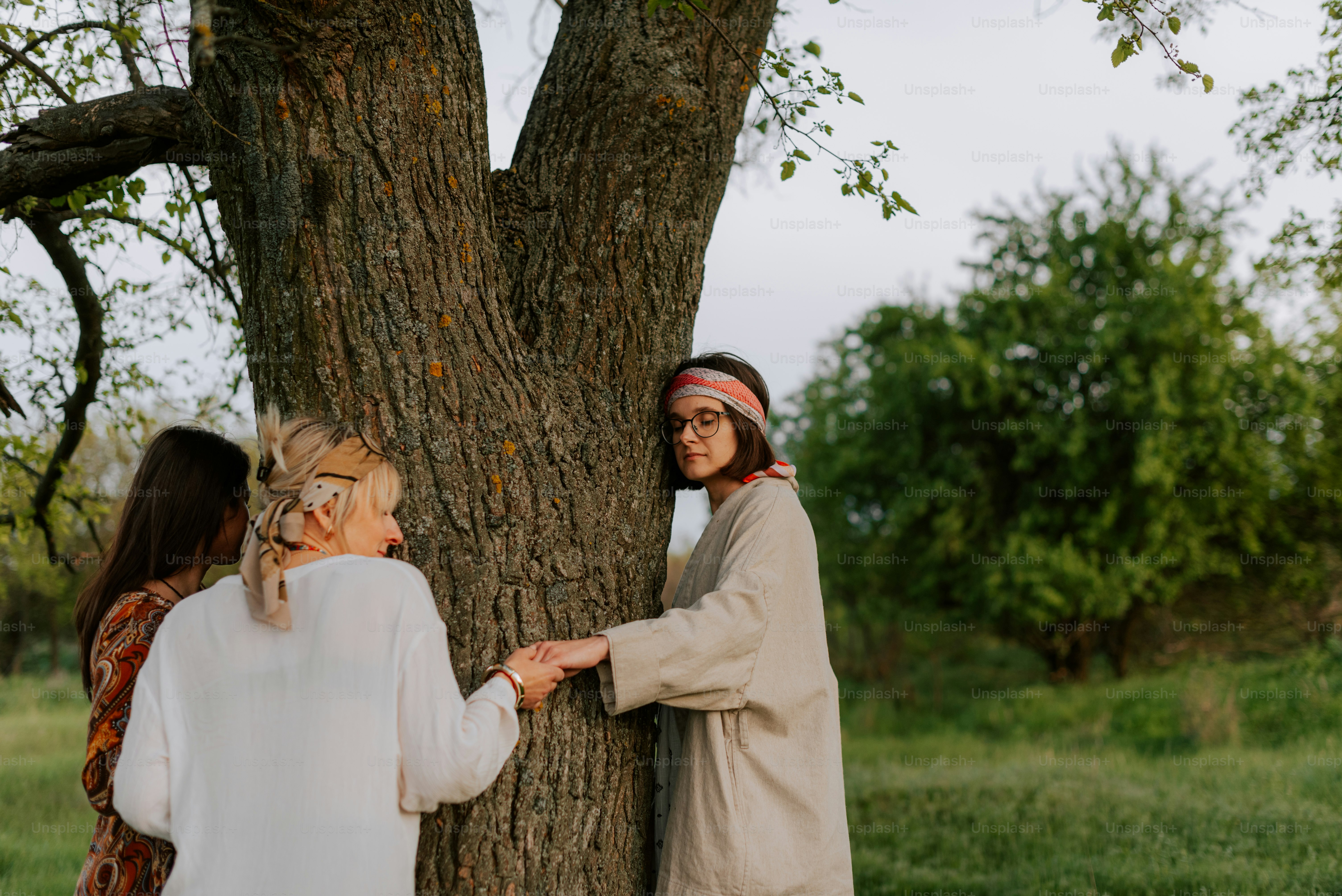 a couple of women standing next to a tree