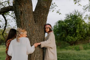 a couple of women standing next to a tree