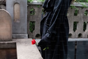 a woman in a black coat holding a red rose