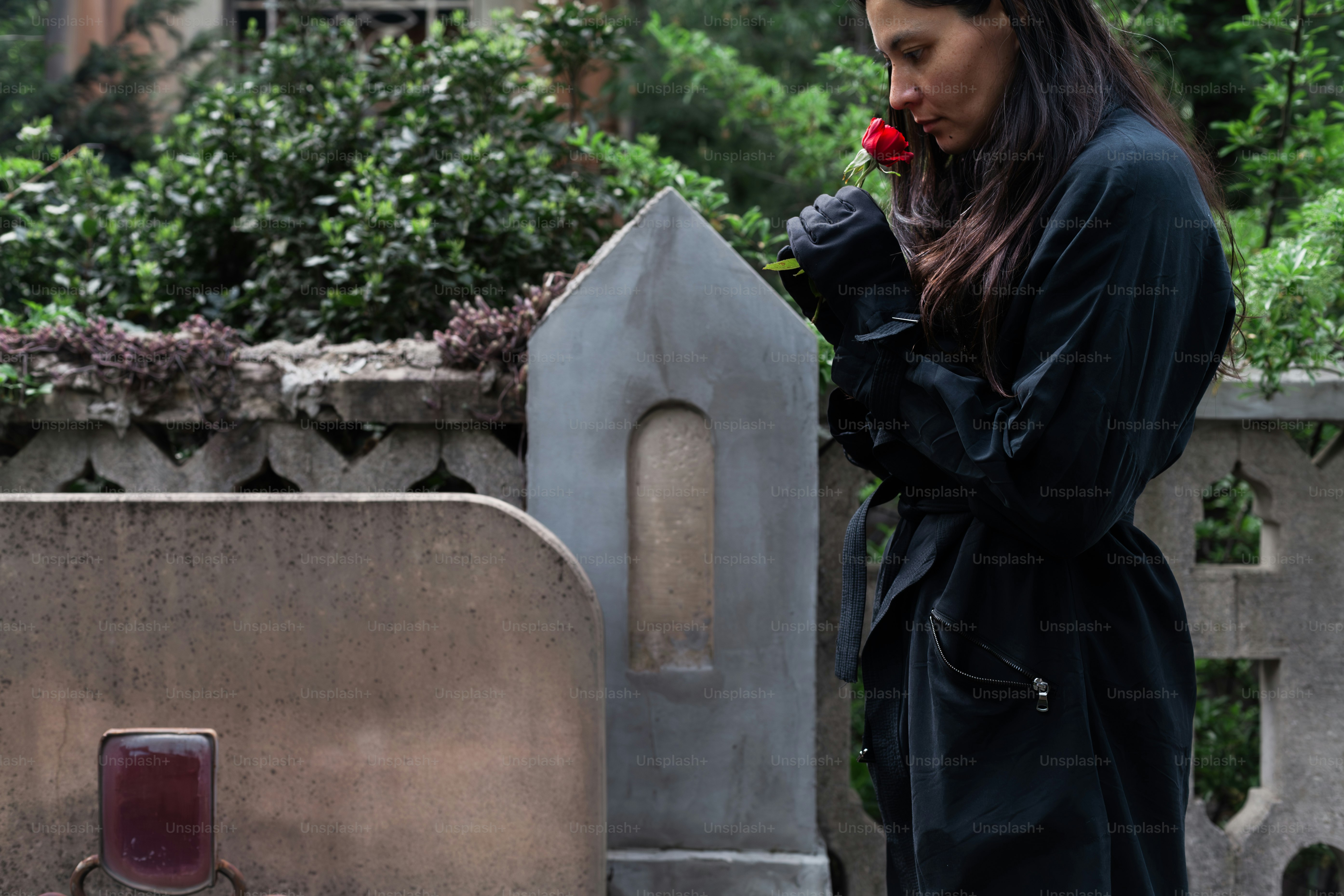 a woman standing next to a grave with a flower in her mouth