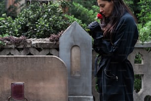 una mujer de pie junto a una tumba con una flor en la boca