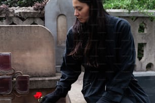 Una mujer coloca una rosa en una tumba
