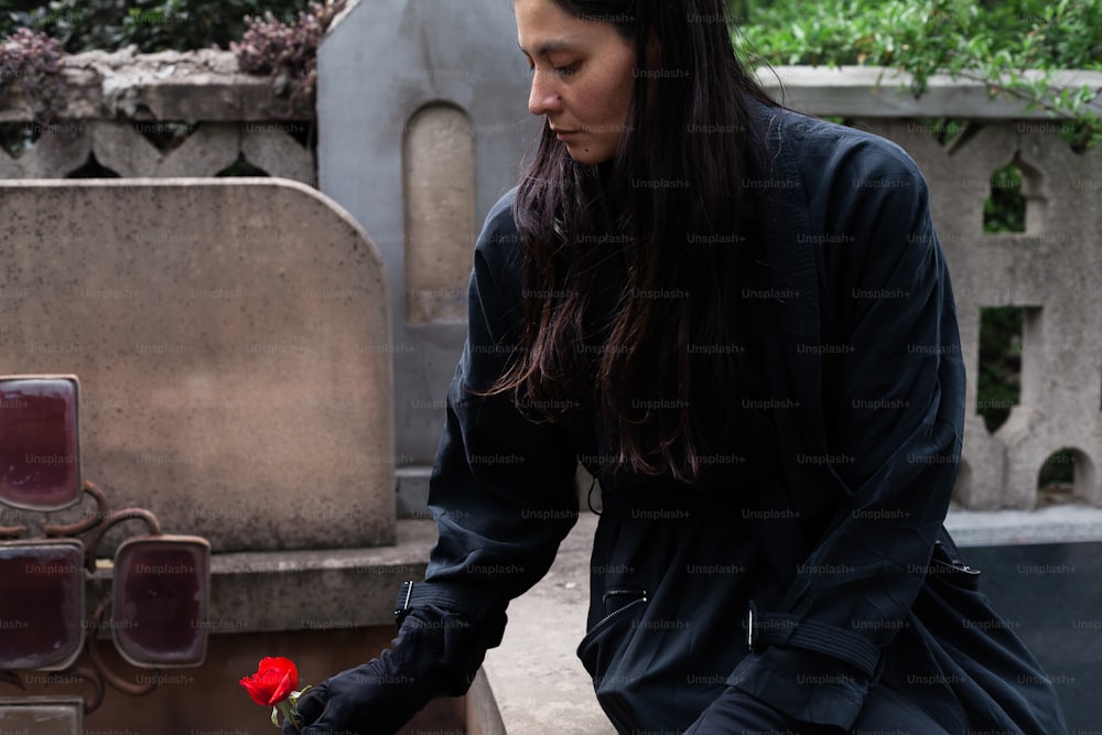 uma mulher coloca uma rosa em uma sepultura