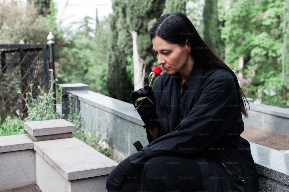 a woman sitting on a cement bench holding a rose