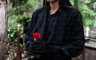 una donna in una giacca nera che tiene una rosa rossa