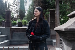 una donna in piedi in un cimitero con una rosa in mano