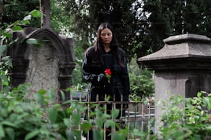 손에 장미를 들고 묘지에 서 있는 여성