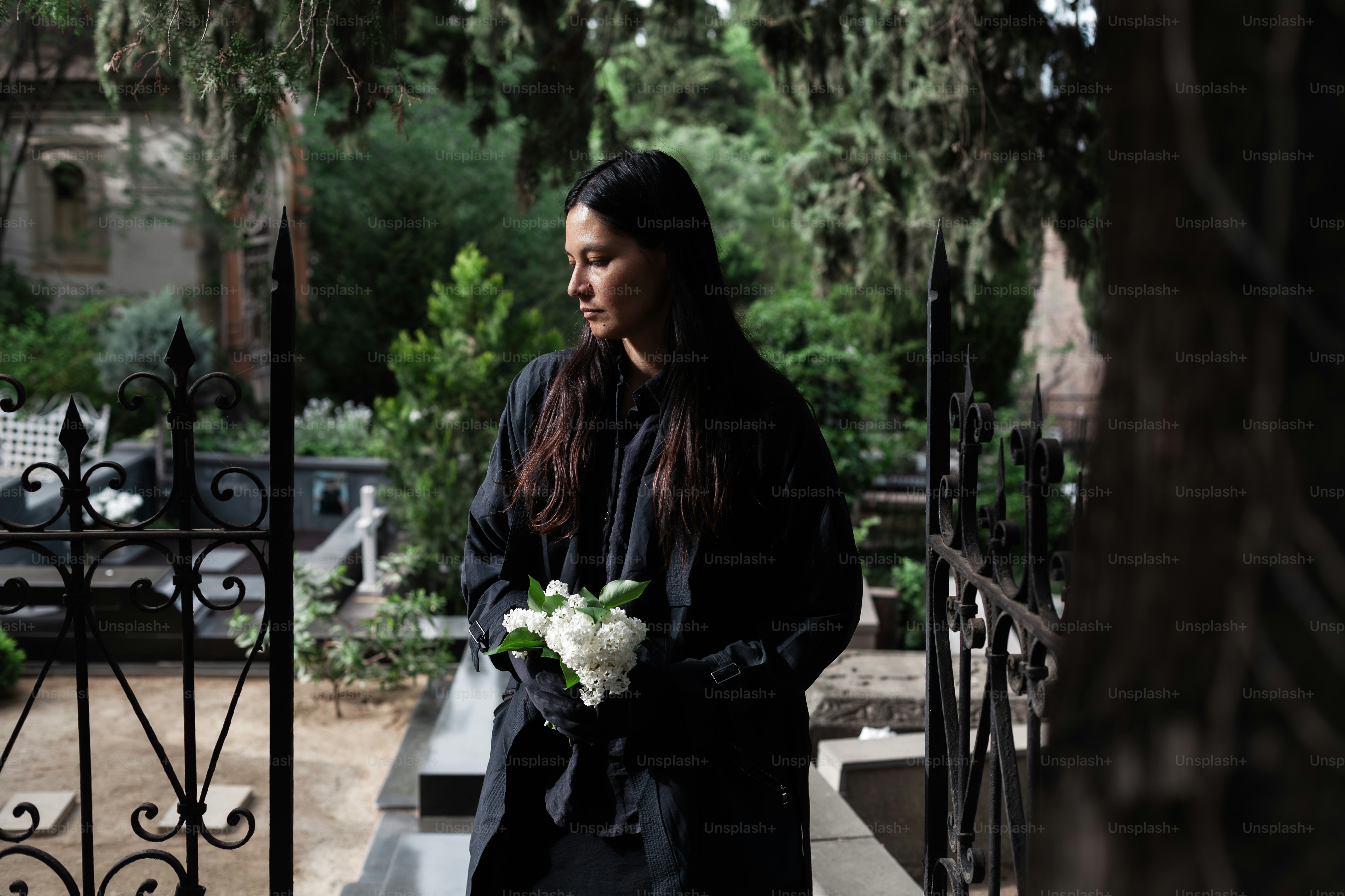 a woman standing in front of a gate holding a bouquet of flowers