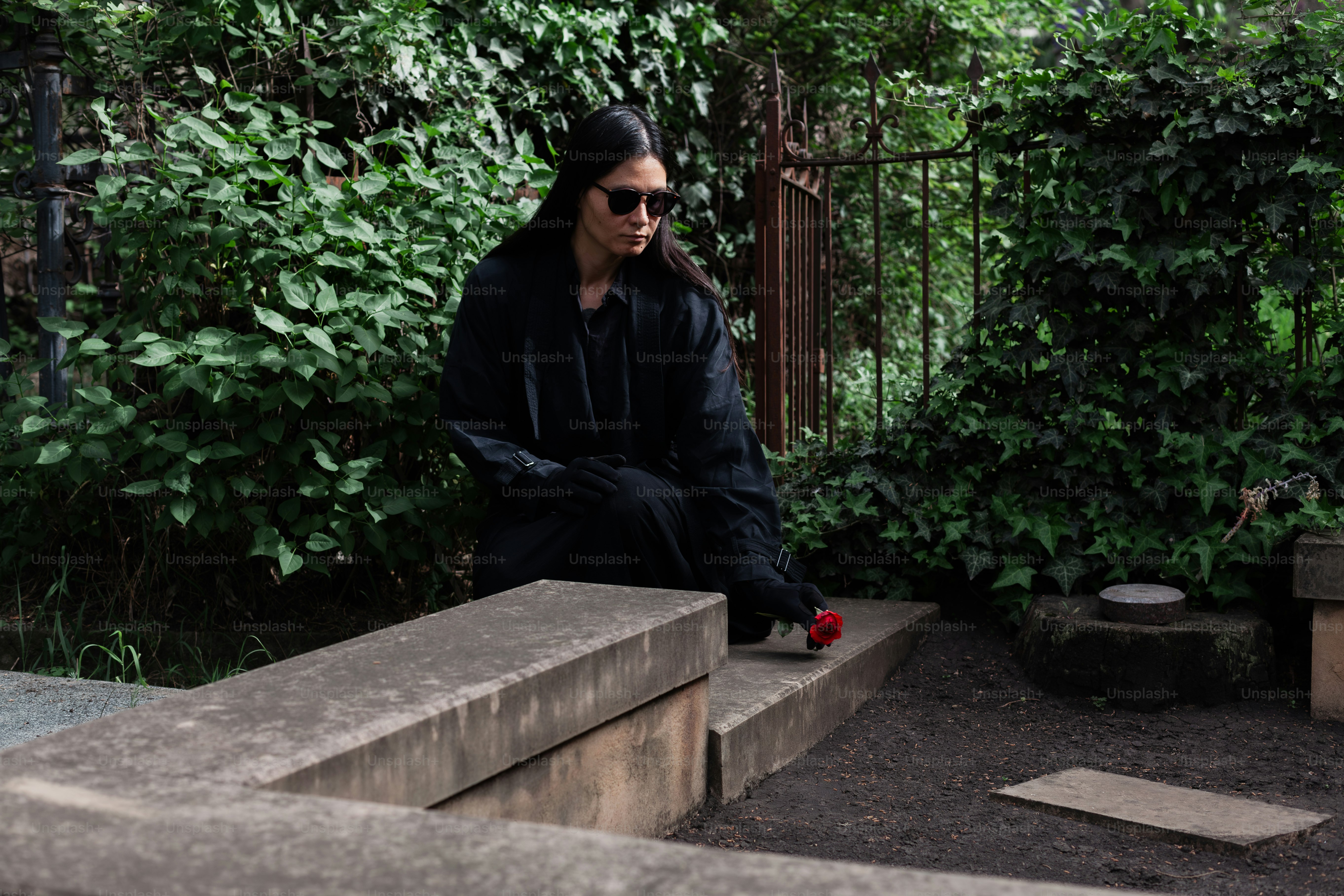 a man sitting on a stone bench in a park