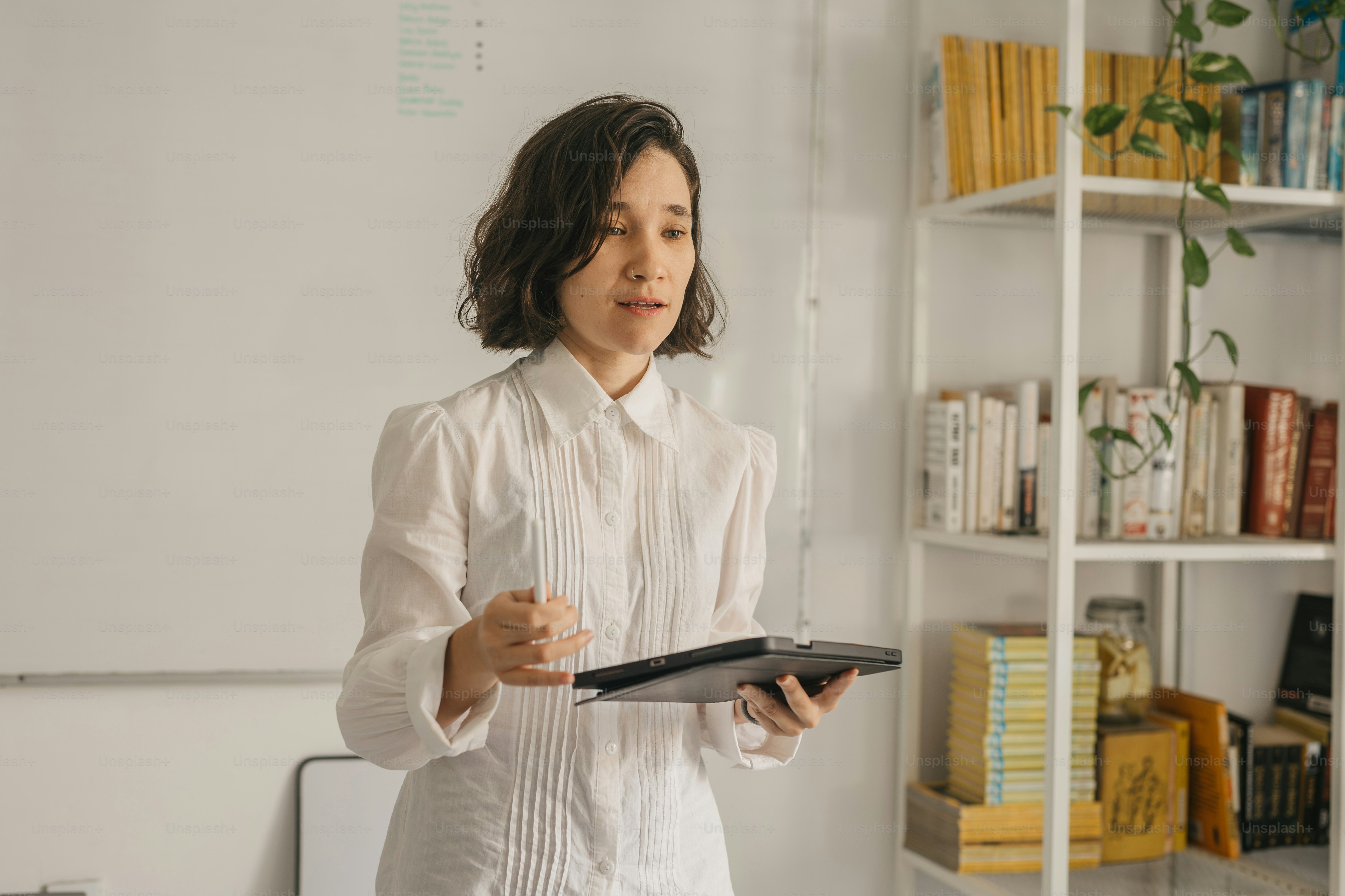 a woman standing in front of a whiteboard holding a tablet