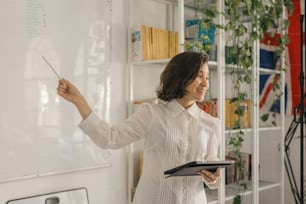 a woman standing in front of a whiteboard holding a clipboard