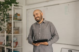 a man standing in front of a whiteboard holding a tablet