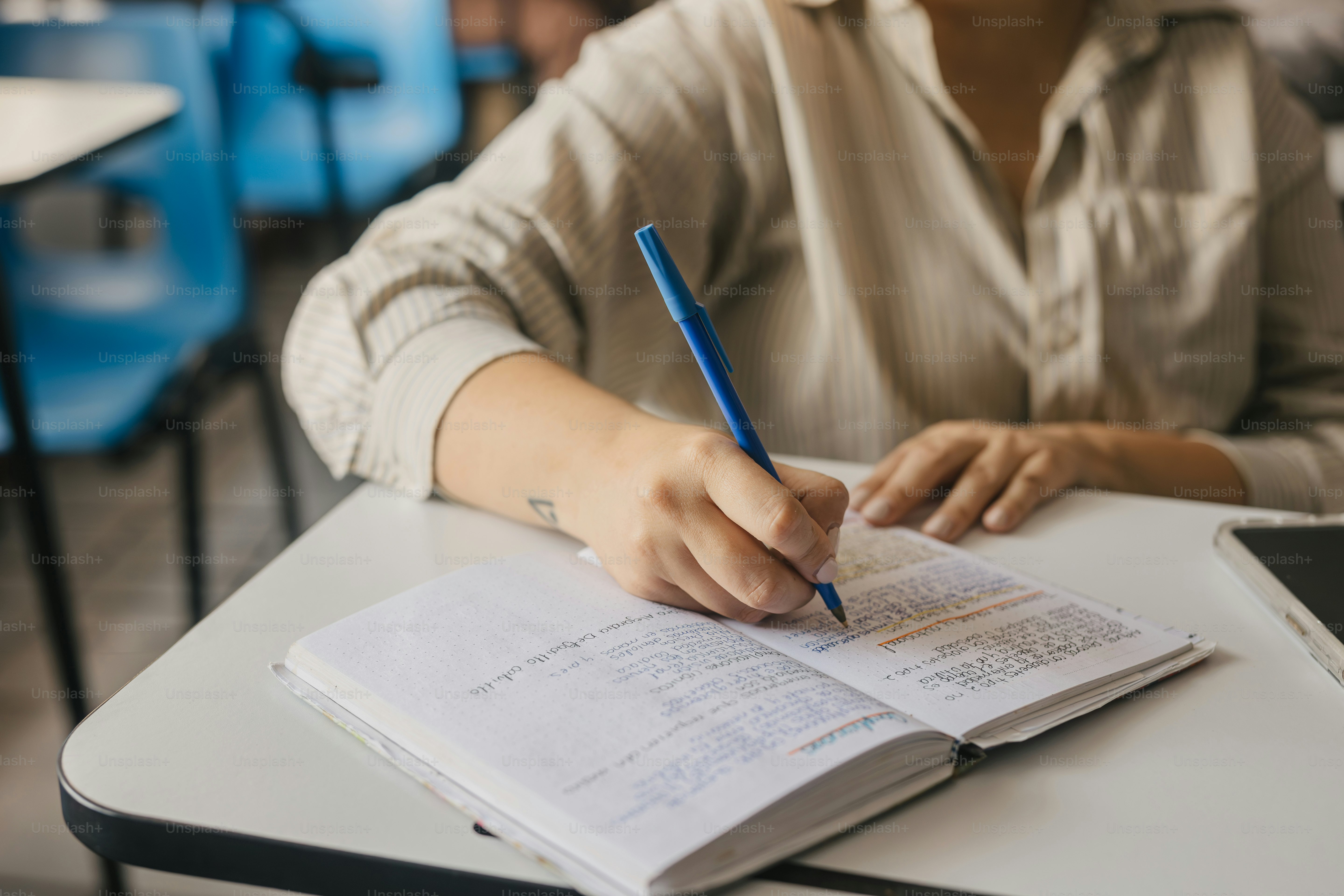 a person sitting at a desk with a book and pen