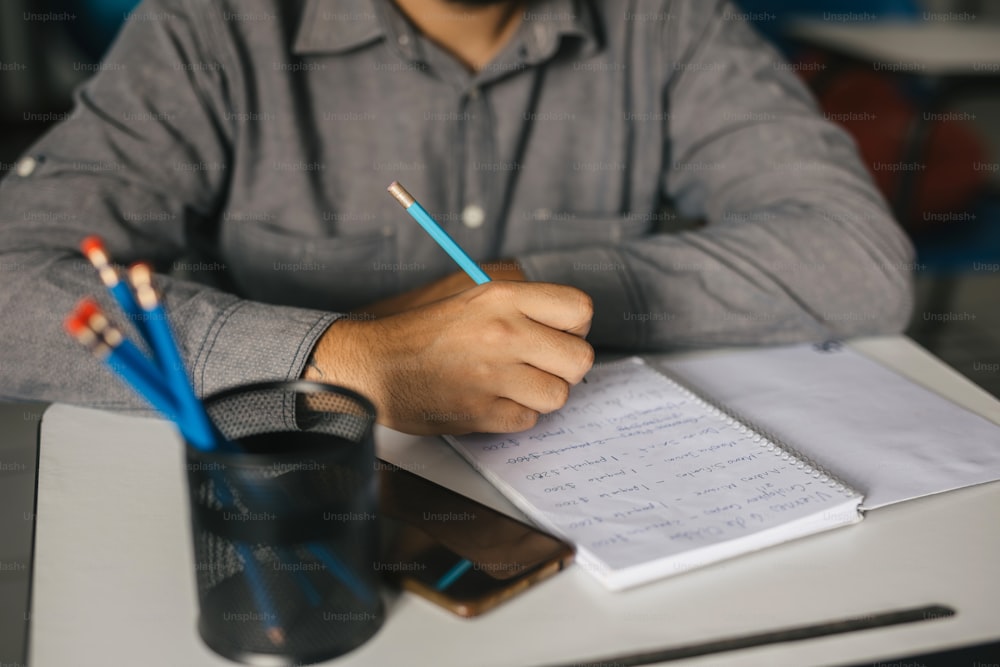 a man sitting at a desk with a notebook and pencils