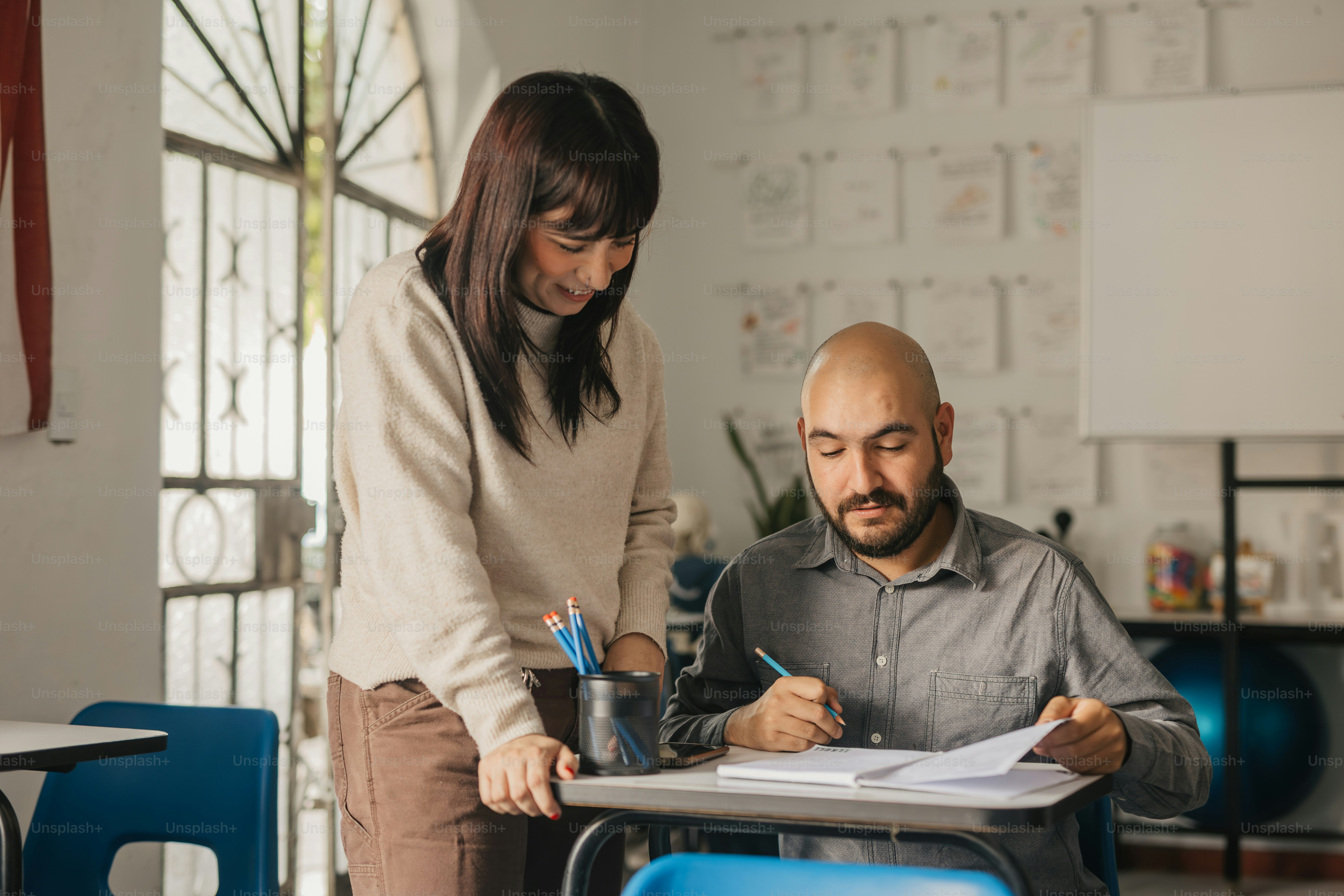 una mujer y un hombre sentados en un pupitre en un aula