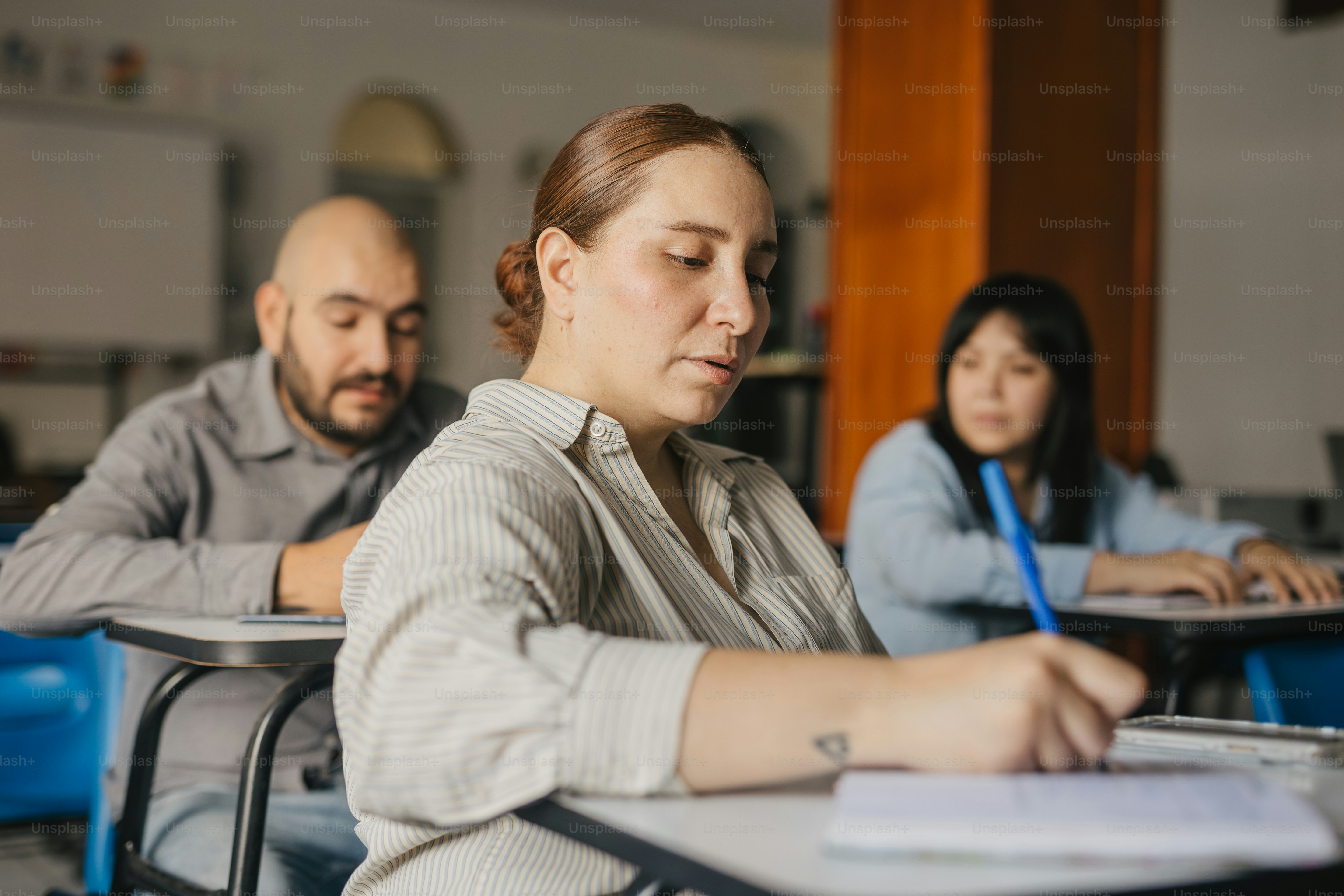 a group of people sitting at desks in a classroom
