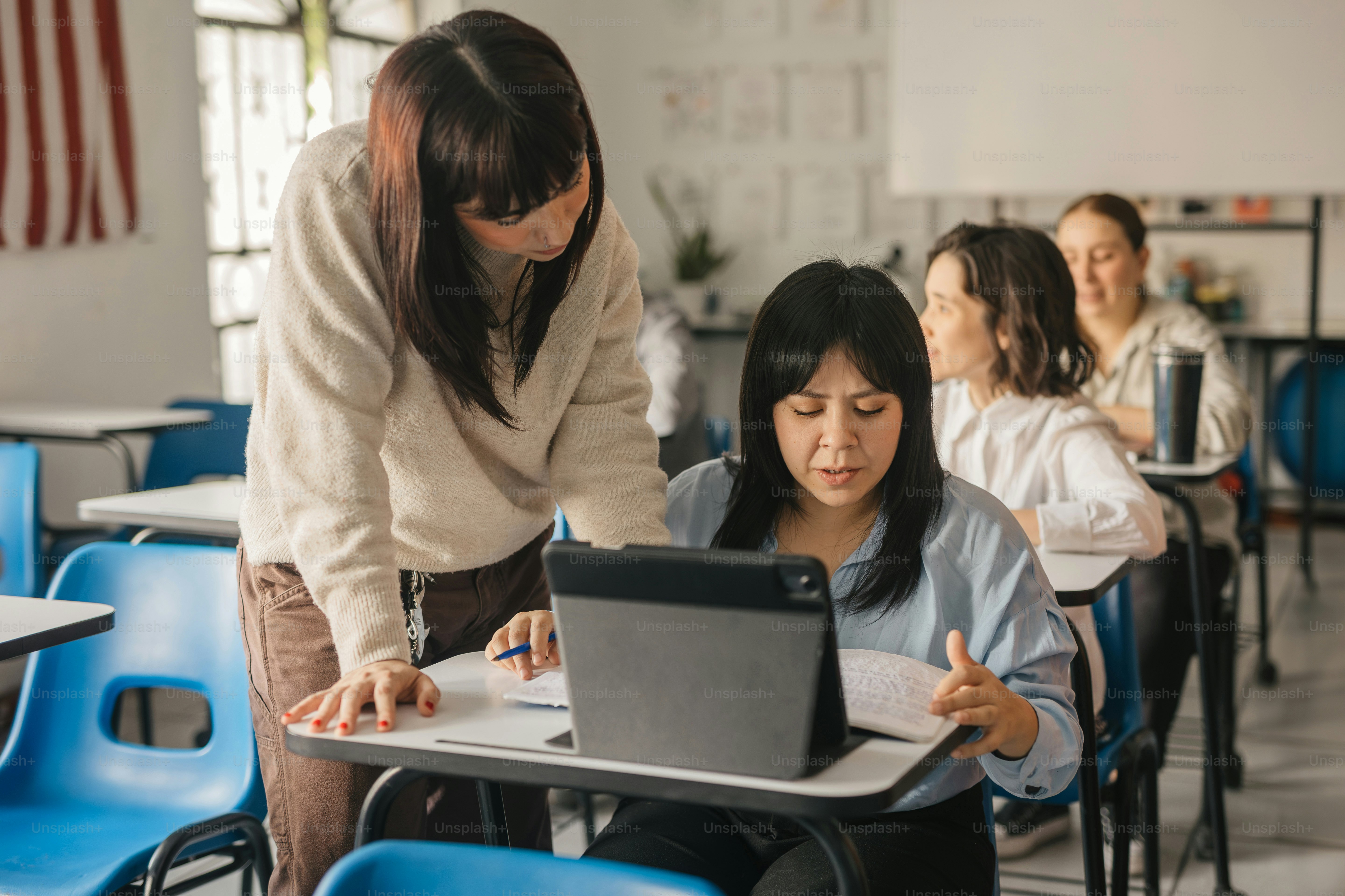 a woman is working on a laptop in a classroom