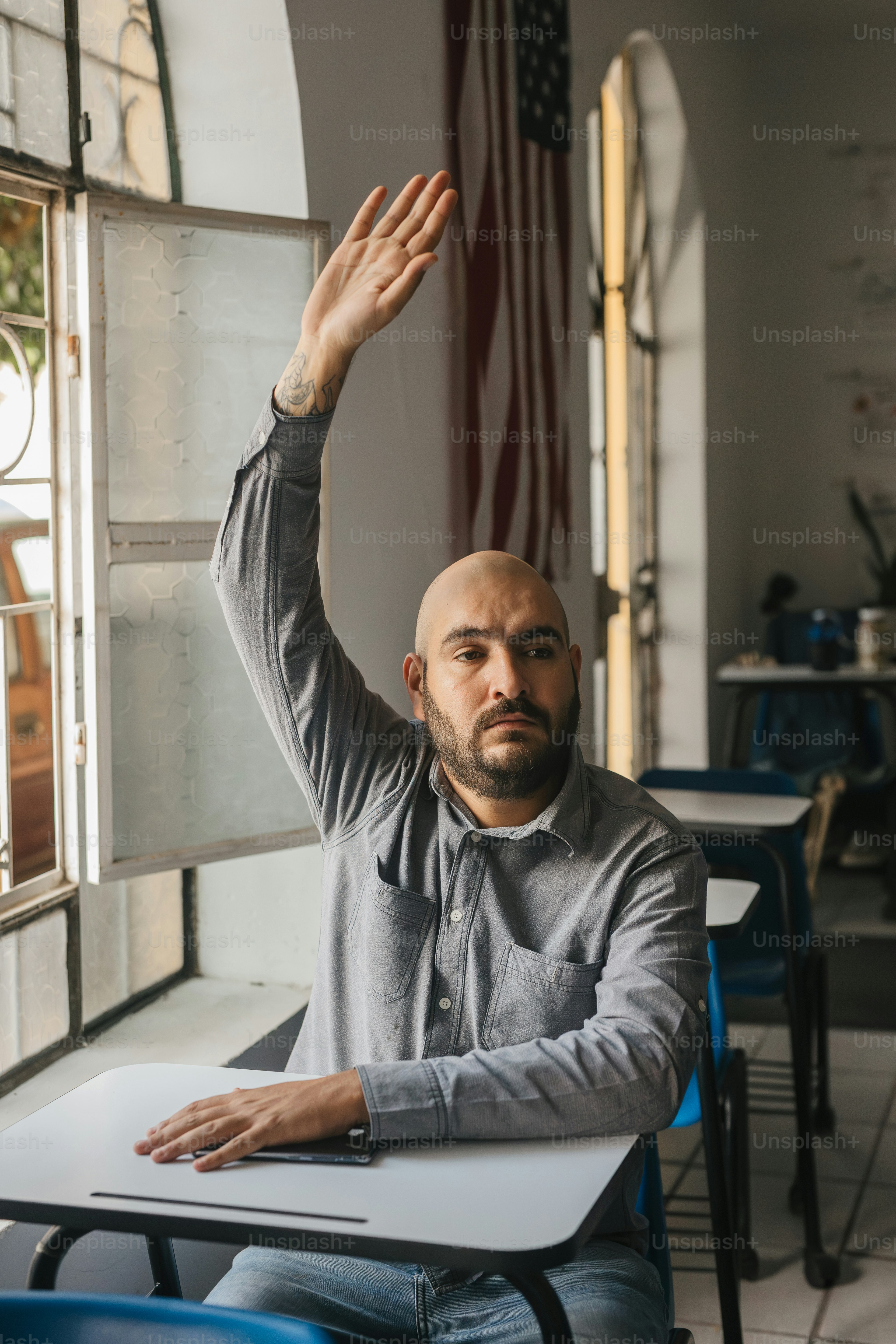 um homem sentado em uma mesa com a mão no ar